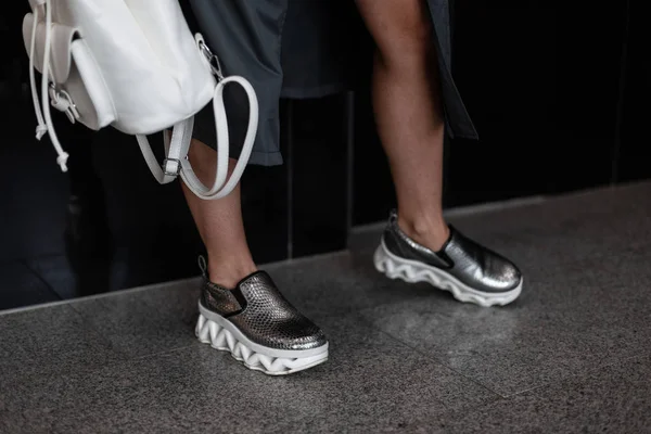 Мода женская одежда. Стильная женская обувь. Свободный дизайн. Крупный план женских ног в серебряных кожаных кроссовках. Уличный стиль . — стоковое фото