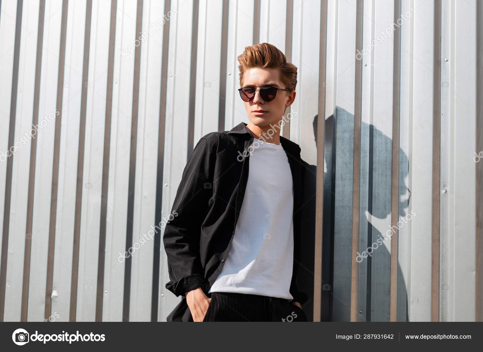 Young cool hipster man with a trendy hairstyle in elegant clothes in fashionable dark sunglasses poses Young cool hipster man with a trendy hairstyle in elegant clothes in fashionable dark sunglasses poses