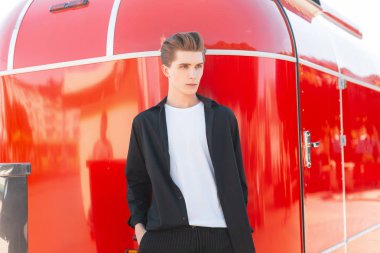 Beyaz bir tişört içinde şık bir saç modeli ile modern zarif genç adam pantolon içinde kırmızı bir Vintage römork yakınında pozlar. Kentsel Avrupa adam moda modeli. Stil.