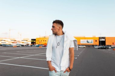 Mavi moda kot bir sweatshirt ile vintage beyaz t-shirt şık bir saç modeli ile genç adam modeli sıcak bir yaz gününde sokakta yürüyor. Şık kentsel adam şehir etrafında bir yürüyüş sahiptir.