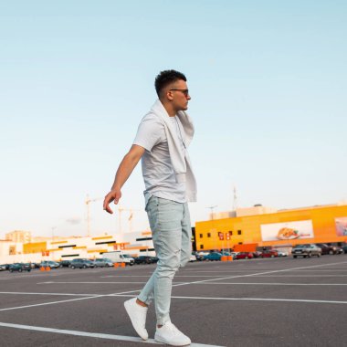 Spor ayakkabı şık bir beyaz t-shirt vintage mavi kot güneş gözlüğü Amerikan genç model adam şehir etrafında yürüyor. Şehirde hipster sokakta yürüyor. Yaz gençlik moda. Moda ya da ben