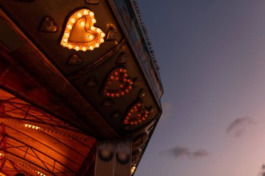 Ampullerden yapılmış kalpli parlak bir vintage atlıkarıncanın bir parçası akşam ışıkları ile parlıyor.