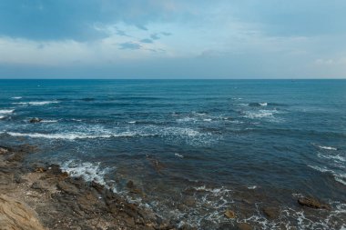 Bulutları ile mavi bir gökyüzü ile kayalar ile dalgalar ile huzursuz deniz. Okyanus ufku. Güzel deniz manzarası.