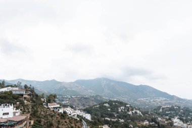 Ağaçlar ve çalılar ile yeşil dağlarda Mijas köyüne tepeden güzel bir görünüm. Mükemmel manzara. Güney İspanya