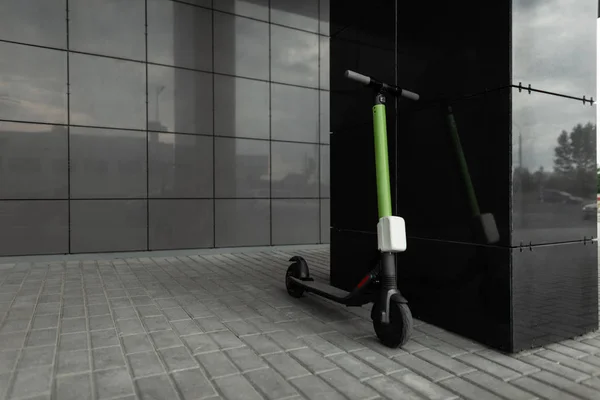 Scooter électrique jaune-noir se dresse sur une rue dans une ville près d'un bâtiment noir. Transports modernes . — Photo