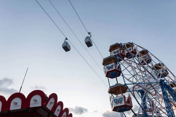 Blick auf den Vergnügungspark mit Karussells mit Riesenrad und zwei Standseilbahnen am Himmel. Gutes Wochenende. — Stockfoto