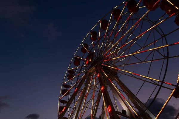 Rueda de hurón gigante con luces brillantes por la noche. Vista inferior de la rueda de la fortuna y el cielo azul oscuro . — Foto de Stock