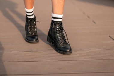 Şık, beyaz çizgili çoraplı, siyah çizmeli kadın bacakları. Son moda gençlik kıyafetleri. Günlük bakışın ayrıntıları. Modern sokak modası. Yakın plan..