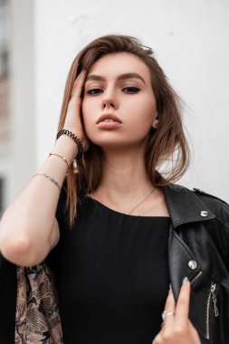Güzel doğal makyajlı ve seksi dudaklı bir kadının portresi. Çekici, oldukça şehvetli, şık siyah elbiseli bir kız model, bir sonbahar günü beyaz bir binanın yanında poz veriyor..