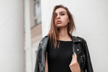 Güzel, seksi, kahverengi saçlı, şık siyah elbiseli bir kadın şehirde klasik bir binanın yanında poz veriyor. Çekici, şehvetli bir kız bir sonbahar günü şehirde yürür. Şık kadın kıyafetleri.