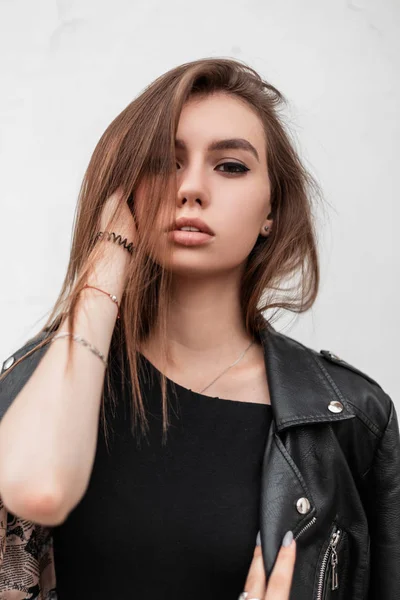 Porträt einer trendigen netten jungen Frau mit schönen Augen mit sexy Lippen und natürlichem Make-up in modischer schwarzer Kleidung vor einer weißen Wand im Freien. attraktive hübsche Mädchen posieren. — Stockfoto