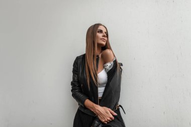 Modaya uygun deri ceketli, beyaz bir arka planda poz veren alımlı, şık bir genç kadın. Güzel şehirli kız model. Yeni sonbahar kadın kıyafetleri koleksiyonu.