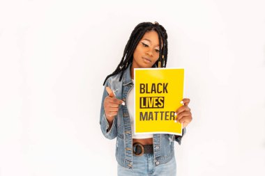 Rasta bukleli genç siyahi kadın, siyah insanları korumak için yazılan protestoların sarı posterini gösteriyor. Motive edici ırkçılığın yeri yoktur ve polis şiddeti vardır. Nefes alamıyorum..