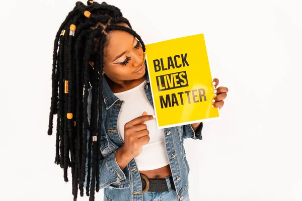 Young african american activist woman went out to support blacks in USA. Black girl holds a yellow poster with with the inscription 