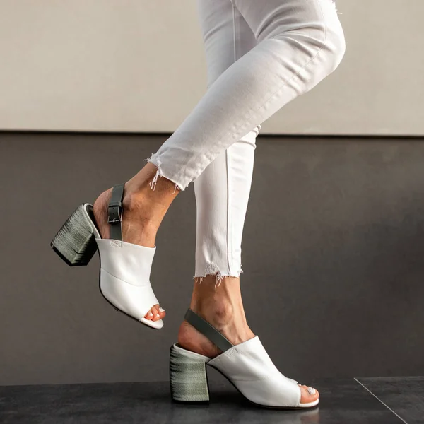 ストリートのヴィンテージビルの近くにスタイリッシュな白いジーンズとファッションレザーの夏の靴を持つ女性の足 — ストック写真