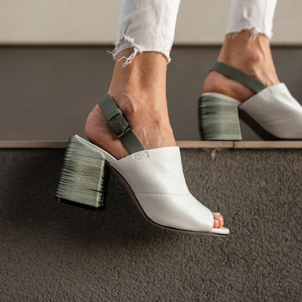 Modaya uygun beyaz deri ayakkabıların kadın bacaklarında yakın plan çekimi..