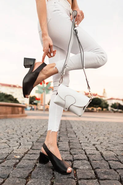 Γυναικεία Πόδια Λευκό Τζιν Μαύρα Δερμάτινα Σανδάλια Τσάντα Πέτρινο Δρόμο — Φωτογραφία Αρχείου