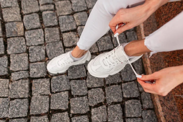 Bovenaanzicht Van Een Modemeisje Witte Jeans Zit Straat Bindt Veters — Stockfoto