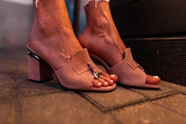 Şehirde akşam vakti, şık yaz bej ayakkabılarının kadın bacaklarının üzerinde yakın plan çekimleri.