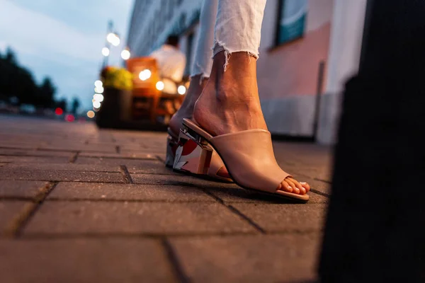 时尚女孩穿着时髦的米黄色夏鞋 晚上站在城里的瓷砖上 关门了 — 图库照片