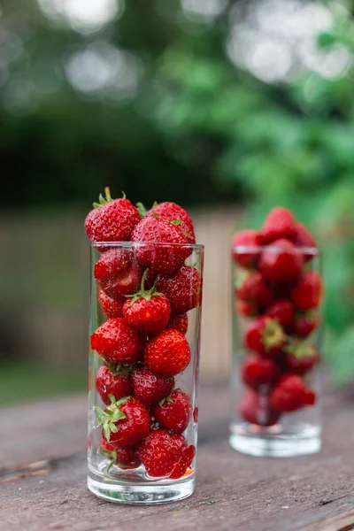 庭の木製のテーブルの上のガラスに新鮮なジューシーなイチゴ 天然いちごジュースのコンセプト — ストック写真