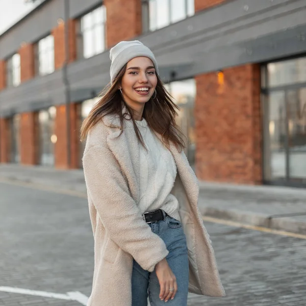 Pretty model of a happy young woman in fashionable casual youth spring outerwear enjoys a walk on the street in the city. Attractive happy girl with a positive smile in trendy clothes. Spring fashion.