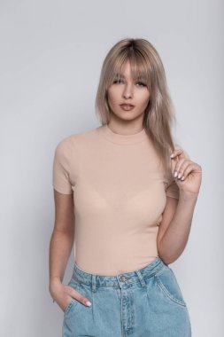 Zarif bir kotla şık bir gömlek içinde şık bir saç stili olan Avrupalı sevimli genç bayan odada klasik beyaz bir duvarın yanında duruyor. Kapalı mekanlarda genç kız kıyafetleri giyen çekici bir kız. Moda bakışı..