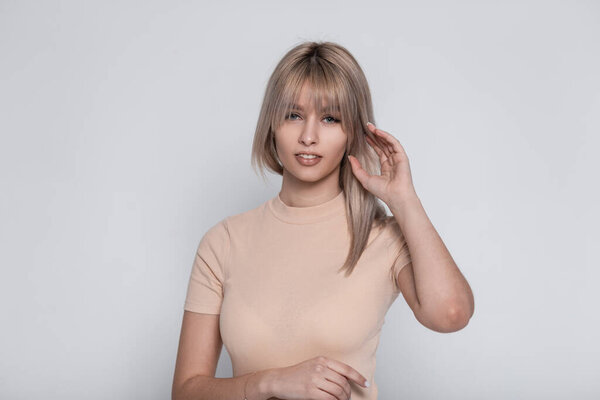 Portrait of a female beautiful face with clean healthy skin with natural make-up with sexy lips with blond hair in an elegant shirt on a white background in studio. Pretty young woman model indoors.