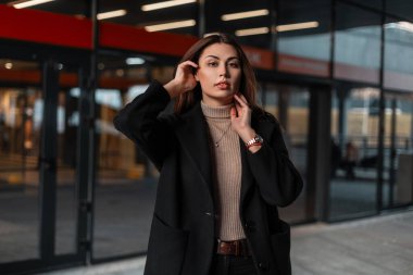 Güzel, esmer bir kadının portresi, doğal makyajı, güzel dudakları olan, siyah, modaya uygun bej gömlekli, cam bir binanın yanında seksi dudakları olan. Şık giyimli şehir kızı mankeni..