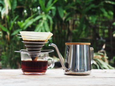 Kahve damlıyor ve ahşap sehpada buzlu kahve var. 