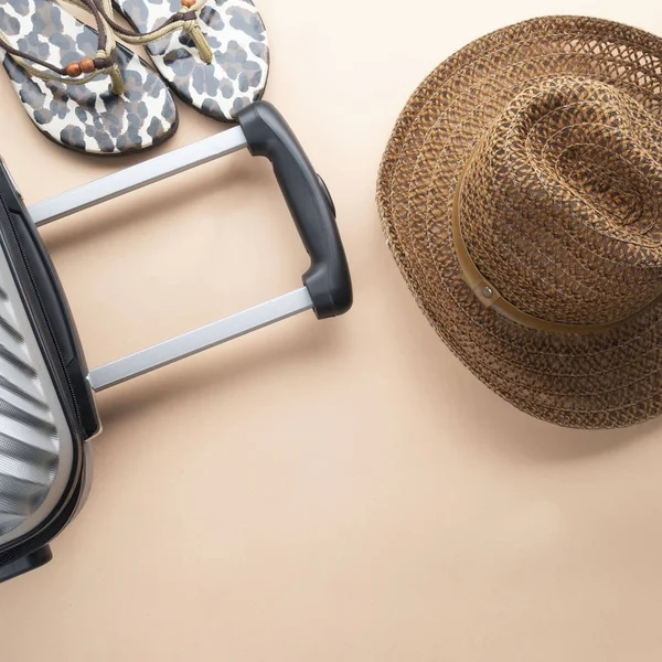 Valise plate grise avec chapeau brun et sandles sur le dos pastel — Photo