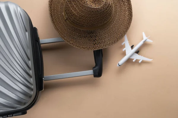 Flat lay grey suitcase with brown hat and mini airplane on paste