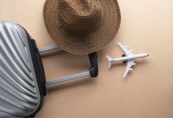 Flat lay grey suitcase with brown hat and mini airplane on paste — Stock Photo, Image