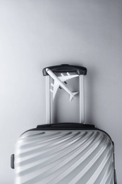 Gri arka planda mini uçak ile düz yatıyordu gri bavul. tr