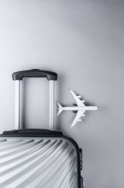 Gri arka planda mini uçak ile düz yatıyordu gri bavul. tr