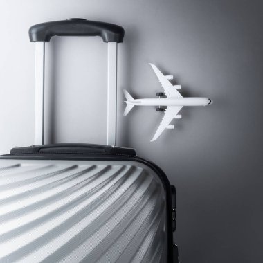 Gri arka planda mini uçak ile düz yatıyordu gri bavul. tr