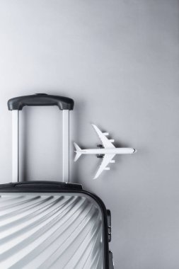 Gri arka planda mini uçak ile düz yatıyordu gri bavul. tr