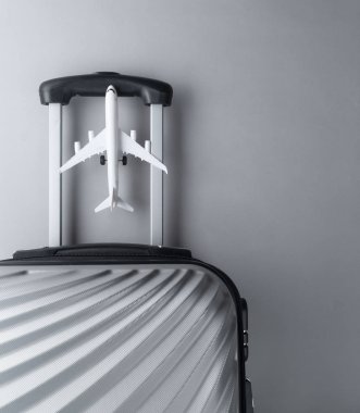 Gri arka planda mini uçak ile düz yatıyordu gri bavul. tr