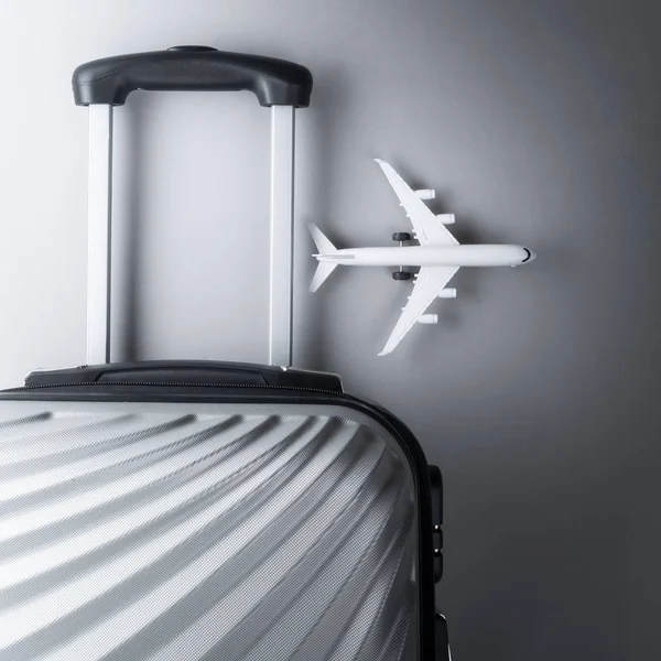 Gri arka planda mini uçak ile düz yatıyordu gri bavul. tr