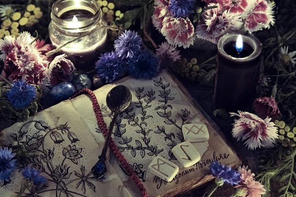 Still life with old book with botanical drawing, black candle and flowers in mystic light. Mystic background with ritual esoteric objects, occult, fortune telling and halloween concept