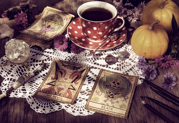 Fortune telling ritual with the tarot cards, pumpkins and cup of tea. Mystic background with ritual objects, occult, fortune telling and halloween concept