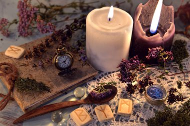 Wooden runes, healing herbs, black and white candles and diary book on lace napkin. Magic ritual. Wicca, esoteric and occult background with vintage witch objects 