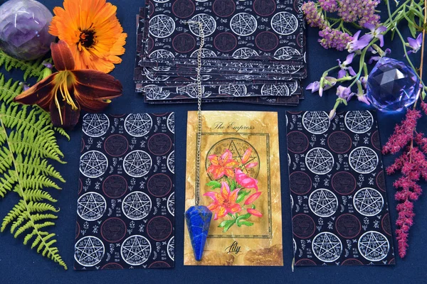 Mystic still life with tarot cards, crystal and flowers on witch table. Esoteric, gothic and occult background with magic objects and herbs. Halloween fortune telling concept.