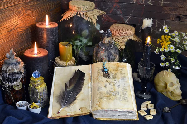 Still life with spell book, magic jars with plants and potion on witch table.  Esoteric, gothic and occult background, Halloween mystic concept.