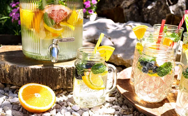 A refreshing cocktail with fruits (grapefruit, orange, lemon, lime) and mint in cocktail mugs and a jug is standing outdoors in the garden. Summer cool drinks. Detox diet, vitamin smoothies