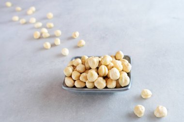 Açık gri beton arka planda gri bir kasede soyulmuş fındık. Taze soyulmuş fındıklar etrafa saçılmış. Doğal organik ürünler kavramı. Vejetaryen yemeği. Üst görünüm