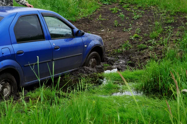 Blue car stuck stuck in mud on off-road in summer car failed to drive through swamp
