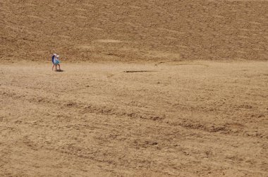 İki kız kardeş, güneşli bir yaz gününde ıssız bir kumsalda fotokopi odasıyla yürür.