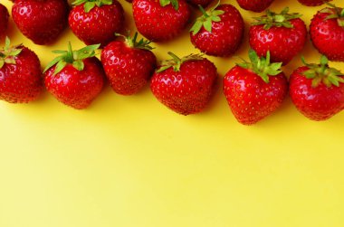 Bir sürü kırmızı çilek sarı arka planda sıralanmış taze, yatay oryantasyon gibi.