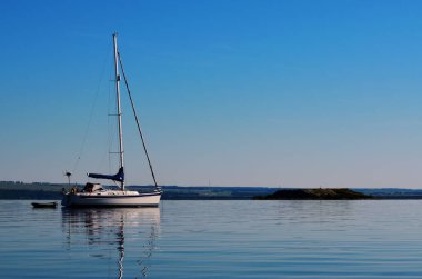 Prusya yatı, şafak vakti küreklerle dolu küçük bir teknenin yanında kıyıya demir atar. Seyahat, turizm, tatil, dinlenme, yaşam tarzı, su taşımacılığı.